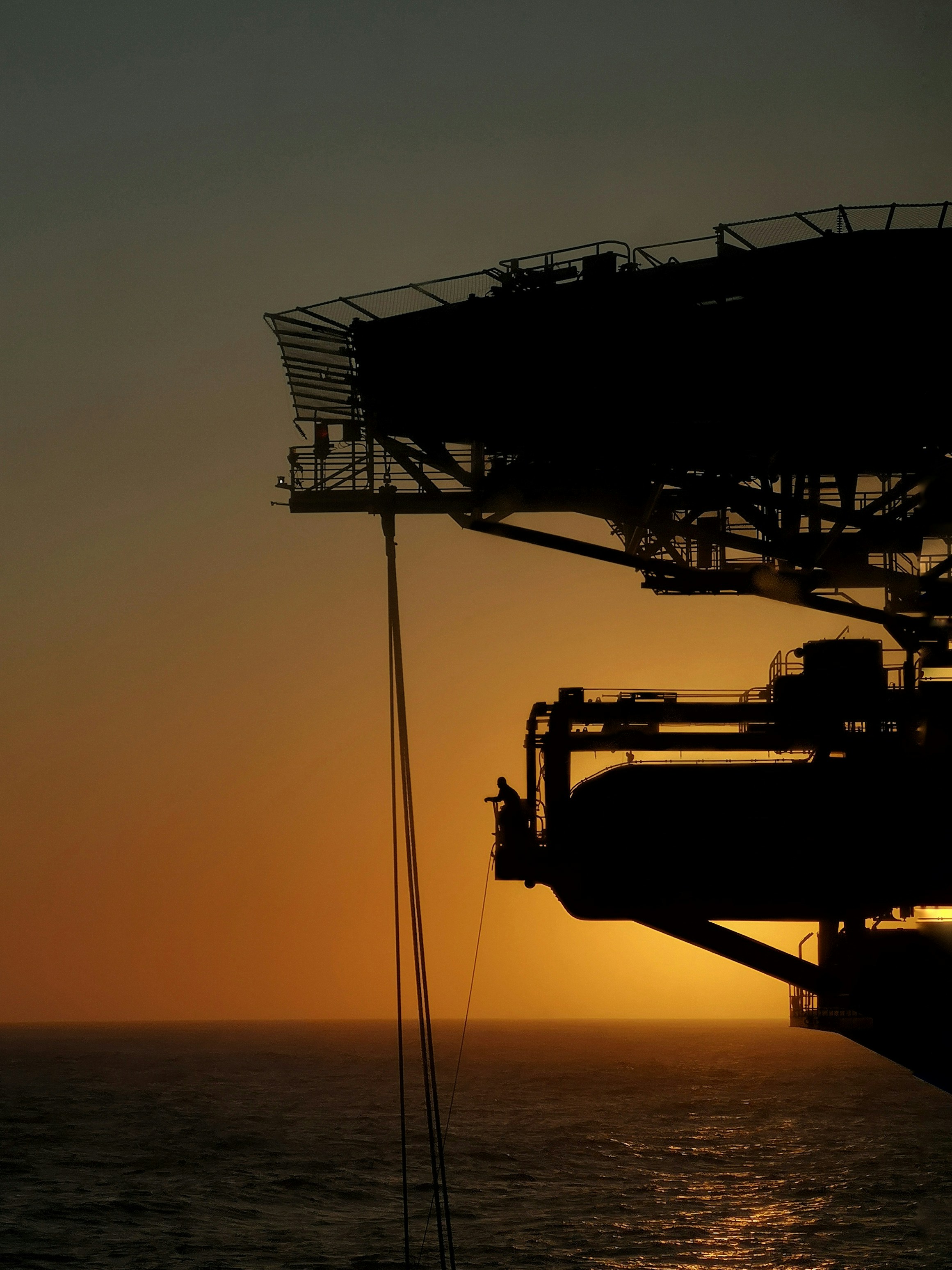 Offshore platform silhouetted against a golden sunset.